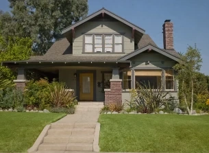 Craftsman-style home with a manicured front lawn, flowering shrubs and a concrete walkway