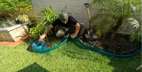 Landscaper digging a trench to set curved edging between the lawn and a planting bed